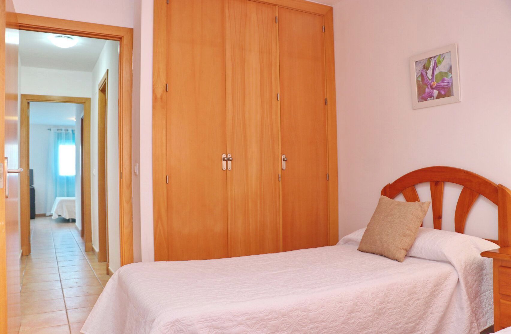 Un dormitorio con cama, armario de madera y mesita de noche.