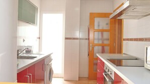 A modern kitchen with a washing machine, a stove, and a microwave. - Apartamento Bateles Cerca de la Playa (Conil de la Fra.)