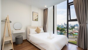 A modern hotel room with a large bed, a wooden ladder, a round mirror, and a city view through large windows. - Eco Green Apartment- Minimalist Home (Ho Chi Minh City)