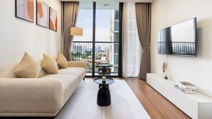 A modern living room with a sofa, a coffee table, and a TV mounted on the wall. - Eco Green Apartment- Minimalist Home (Ho Chi Minh City)