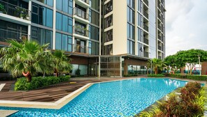 A modern building with a swimming pool, surrounded by lush greenery and a wooden deck. - Eco Green Apartment- Minimalist Home (Ho Chi Minh City)