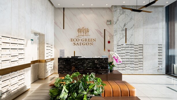 A modern reception area with a marble wall, a reception desk, and a plant. - Eco Green Apartment- Minimalist Home (Ho Chi Minh City)