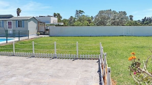 A fenced yard with a swimming pool, a white building, and a clear sky. - Bungalow Puntalejo in Conil (Conil de la Frontera)