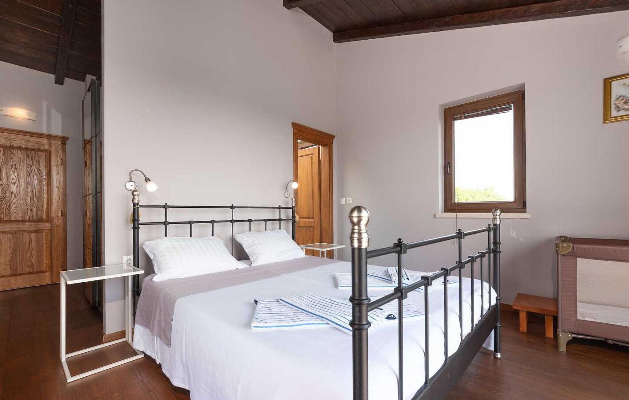 A bedroom with a bed, bedside tables, a window, and a wooden wardrobe.