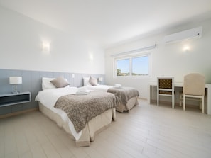 Una habitación de hotel moderna con dos camas, un escritorio, una silla y ventana con vistas.