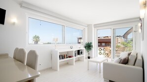 Un ambiente luminoso e bianco con angolo ristoro, divano e libreria.