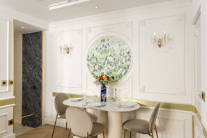 Un coin repas avec une table ronde, des chaises, un vase de fleurs et des appliques murales.