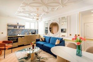 Un salon moderne avec un canapé bleu, une table basse en verre et un coin repas doté d’une table blanche.