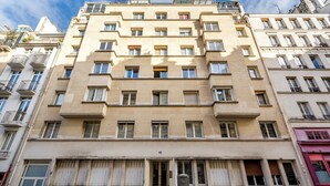 Ein mehrstöckiges Gebäude mit einer symmetrischen Fassade, großen Fenstern und Balkonen.