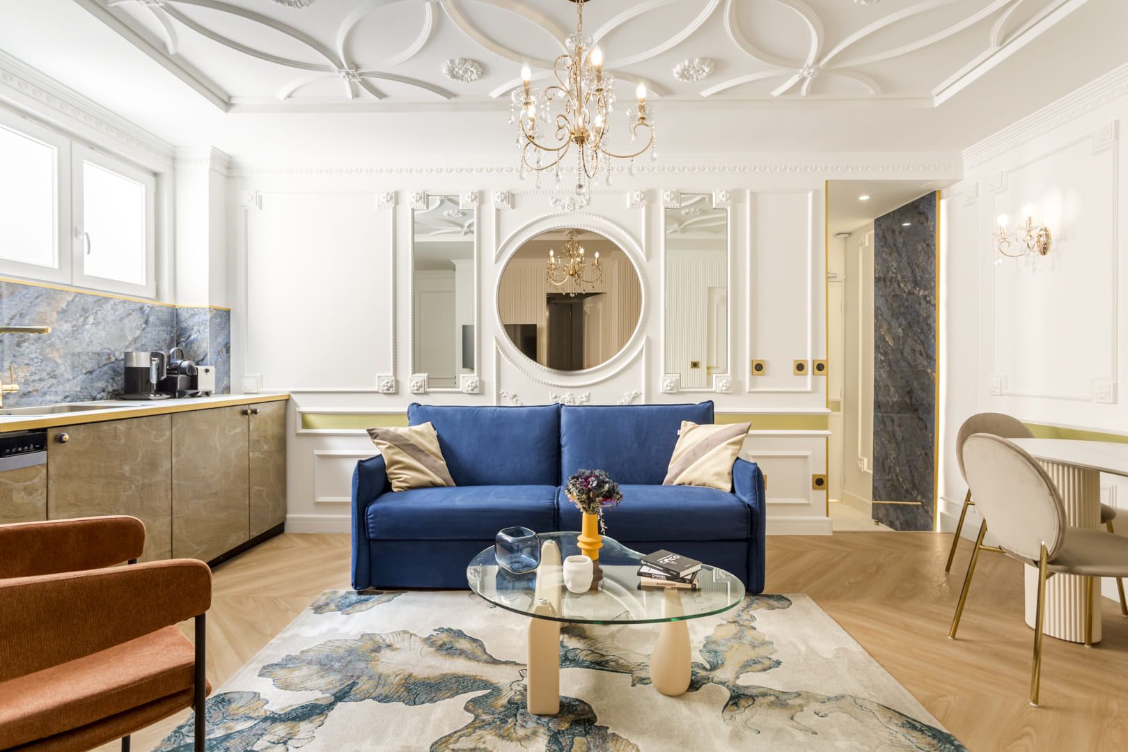 Un salon moderne avec un canapé bleu, une table basse en verre et un lustre.