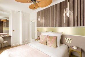 Une chambre à coucher avec un grand lit, un bureau avec une chaise, un miroir et un ventilateur de plafond.