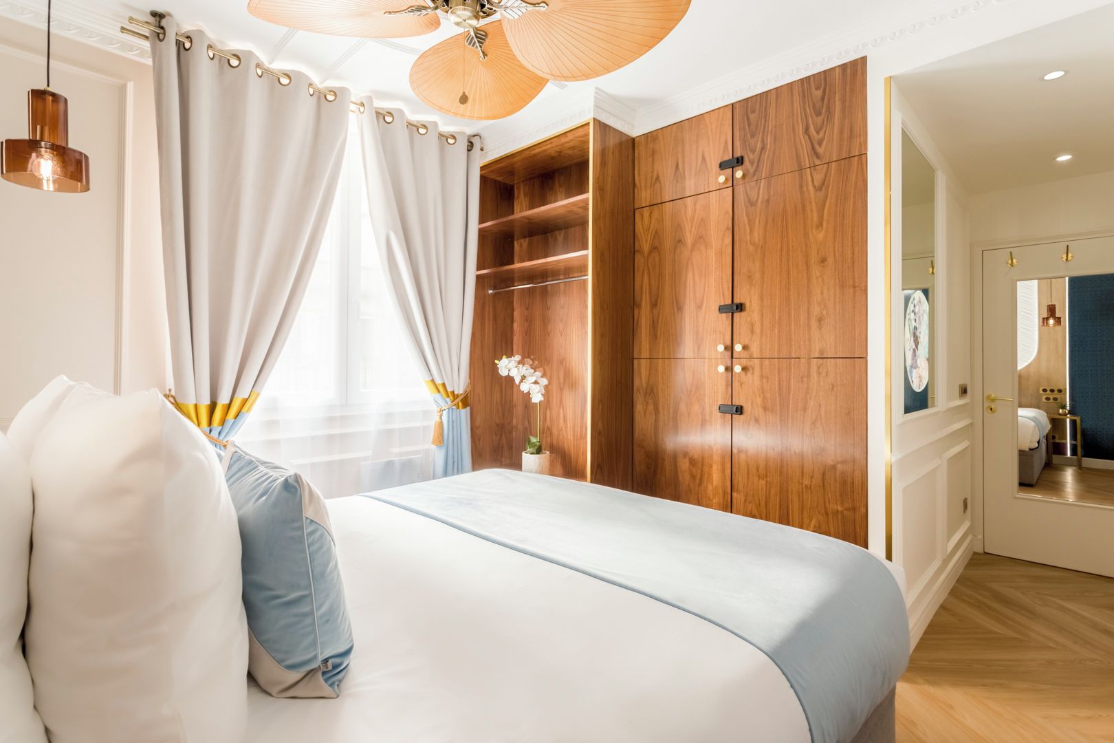 A modern bedroom with a bed, curtains, a ceiling fan, and a wardrobe.