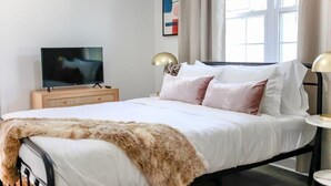 Ein modernes Schlafzimmer mit Bett, Fernseher und Nachttisch.