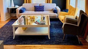 A living room with a sofa, armchair, coffee table, and a ceiling fan. - Cozy house in Bishop District (Dallas)