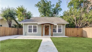 A single-story house with a front porch, a front yard with a concrete pathway, and a wooden fence. - Cozy house in Bishop District (Dallas)