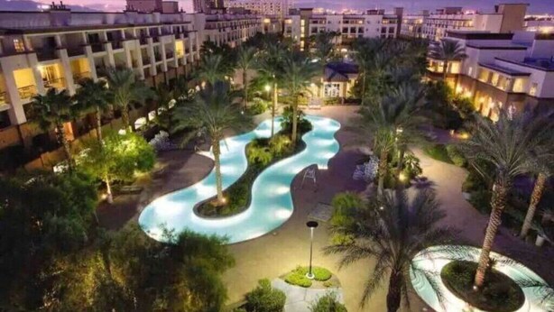 A resort with a winding pool, palm trees, and modern buildings. - Perfect Super Bowl Week Condo - 10 minutes from stadium (Las Vegas)