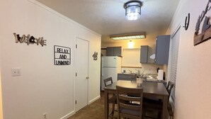 Una cocina compacta con comedor, refrigerador y lámpara en el techo.