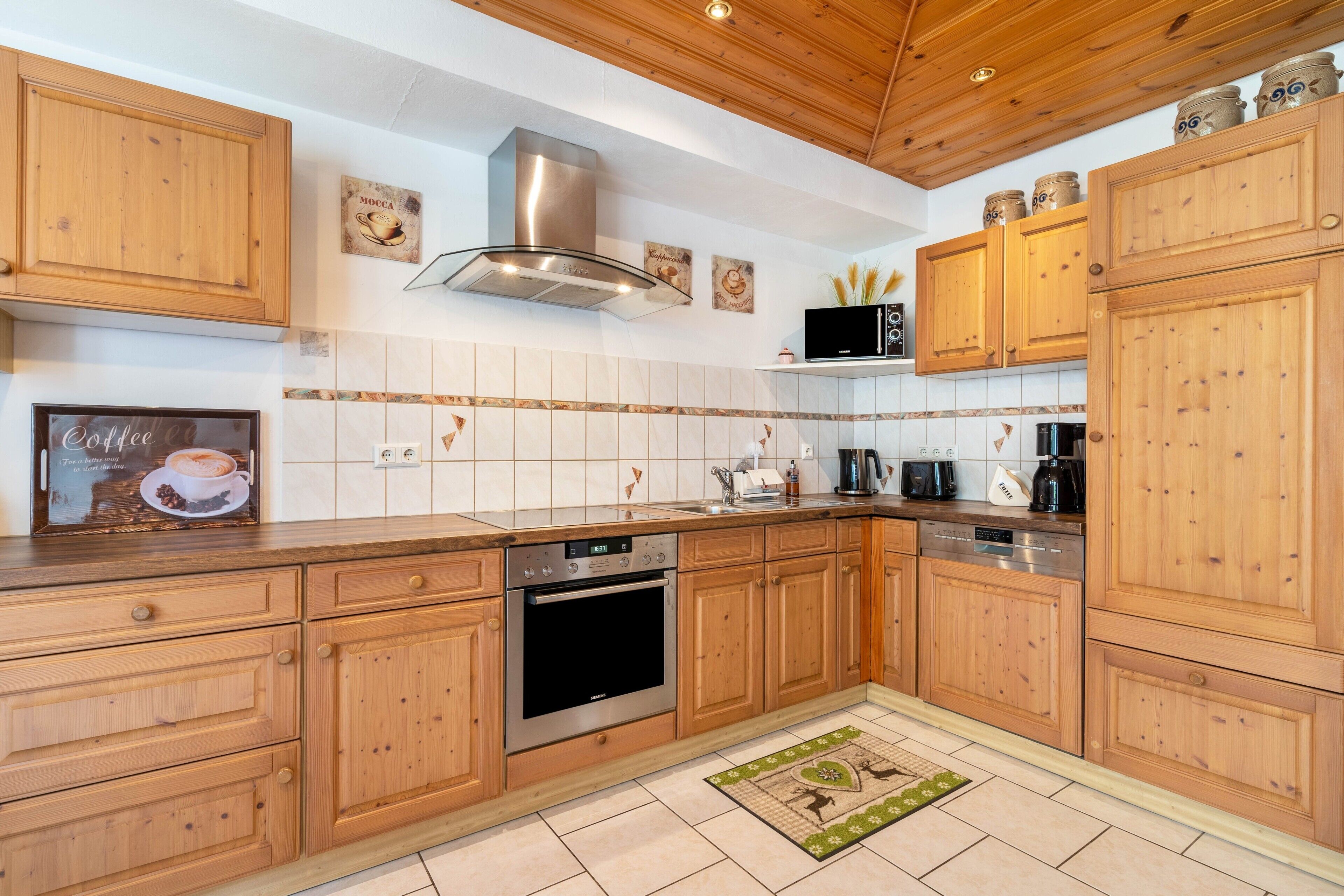 A kitchen with wooden cabinets, a stainless steel range hood, a dishwasher, and a coffee maker.