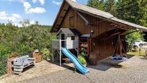 Une structure en bois comprenant un toboggan, une balançoire et une cabane de jeux.