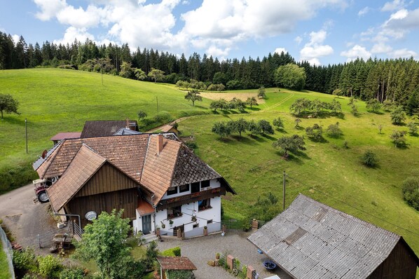 A rural house with a sloped roof, a small porch, and a gravel driveway.