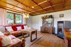 A cozy living room with a red sofa, wooden table, and a vintage stove.