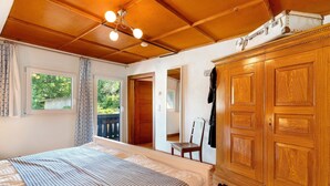 Une chambre à coucher avec un lit, une armoire en bois et une fenêtre avec des rideaux.