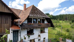 Une maison à deux étages, avec un toit en pente, un revêtement extérieur en bois et un balcon agrémenté de jardinières.