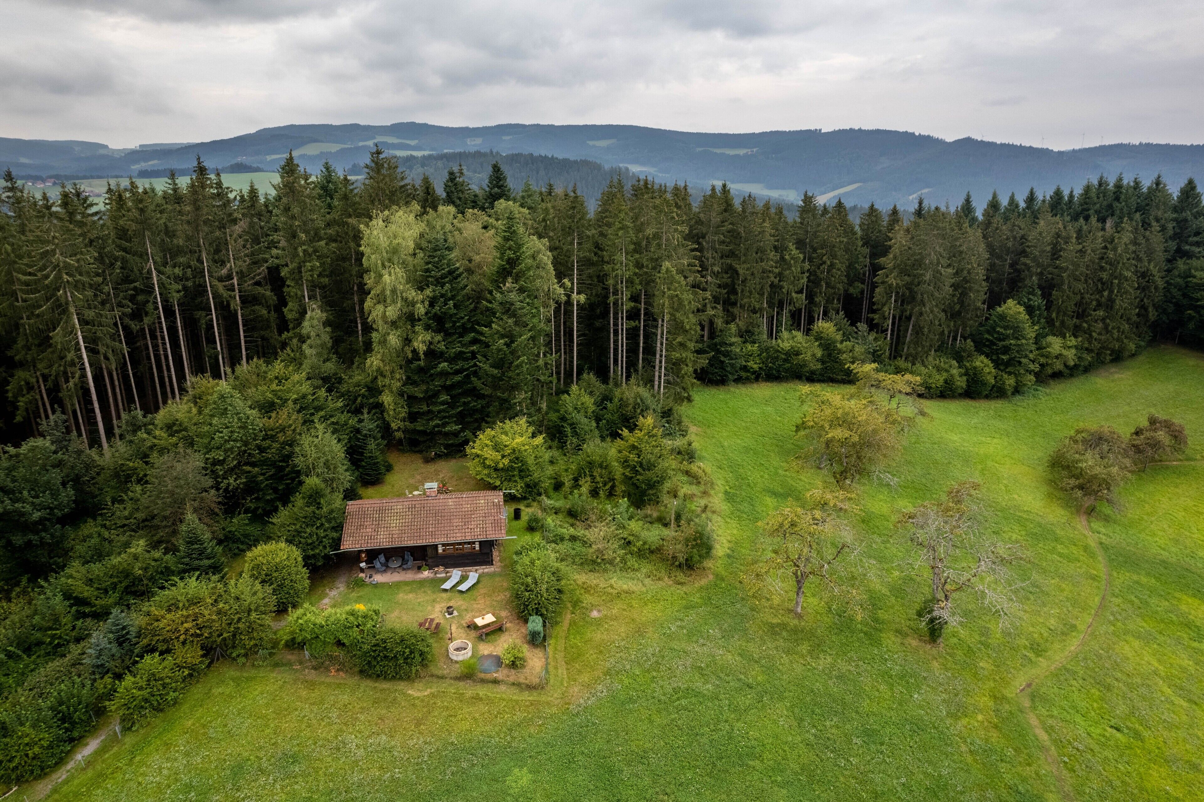 Et hus omgivet af skov med udsigt til fjerne bjerge.