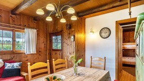 A wooden cabin interior with a dining table, chairs, a vase with flowers, a clock, and a bunk bed. - Holiday Home 'Blockhaus Paepke' with Private Terrace and Private Garden (Mühlenbach)