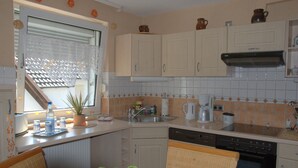 Une cuisine compacte avec des meubles blancs, un lave-vaisselle, une cuisinière et une fenêtre donnant sur un beau paysage.