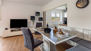 Une cuisine moderne avec un coin repas, un téléviseur à écran plat et une grande fenêtre.