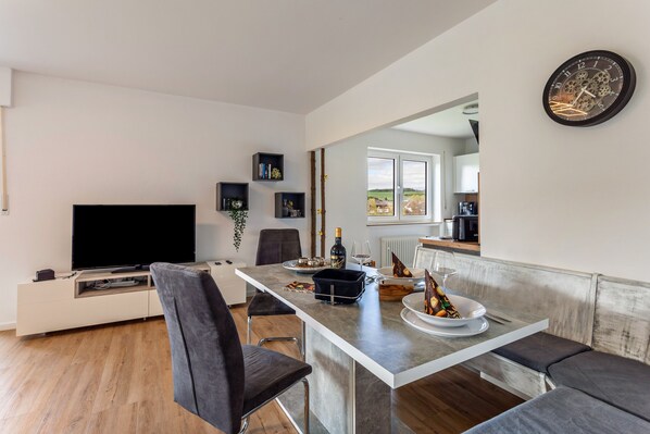 Una cocina moderna con comedor, televisor de pantalla plana y un amplio ventanal.