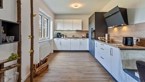 Une cuisine moderne avec des armoires blanches, un plan de travail en bois et un four encastré.