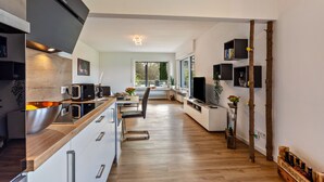 Une cuisine moderne avec un plan de travail en bois, des appareils électroménagers intégrés et une vue sur l’extérieur.