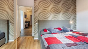 Une chambre moderne avec un grand lit, une tête de lit et un mur orné d’un motif.
