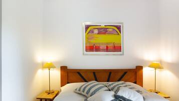 Un letto con testiera in legno, due lampade sui comodini e un quadro appeso al muro.