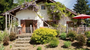 A traditional house with a wooden fence, a red umbrella, and a garden with various plants. - Holiday Home 'Ferienhaus Auszeithaus' with Private Terrace, Private Garden and Wi-Fi (Zell/Ebenhausen)