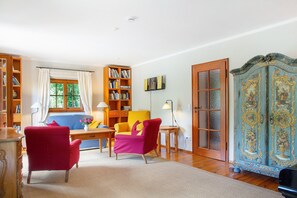A room with a bed, two chairs, a bookshelf, a cabinet, and a window. - Holiday Home 'Ferienhaus Auszeithaus' with Private Terrace, Private Garden and Wi-Fi (Zell/Ebenhausen)