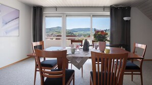 A dining area with a table, chairs, and a view of the countryside. - Apartment 'Ferienwohnung Lange' with Mountain View, Balcony and Wi-Fi (Waldstetten)
