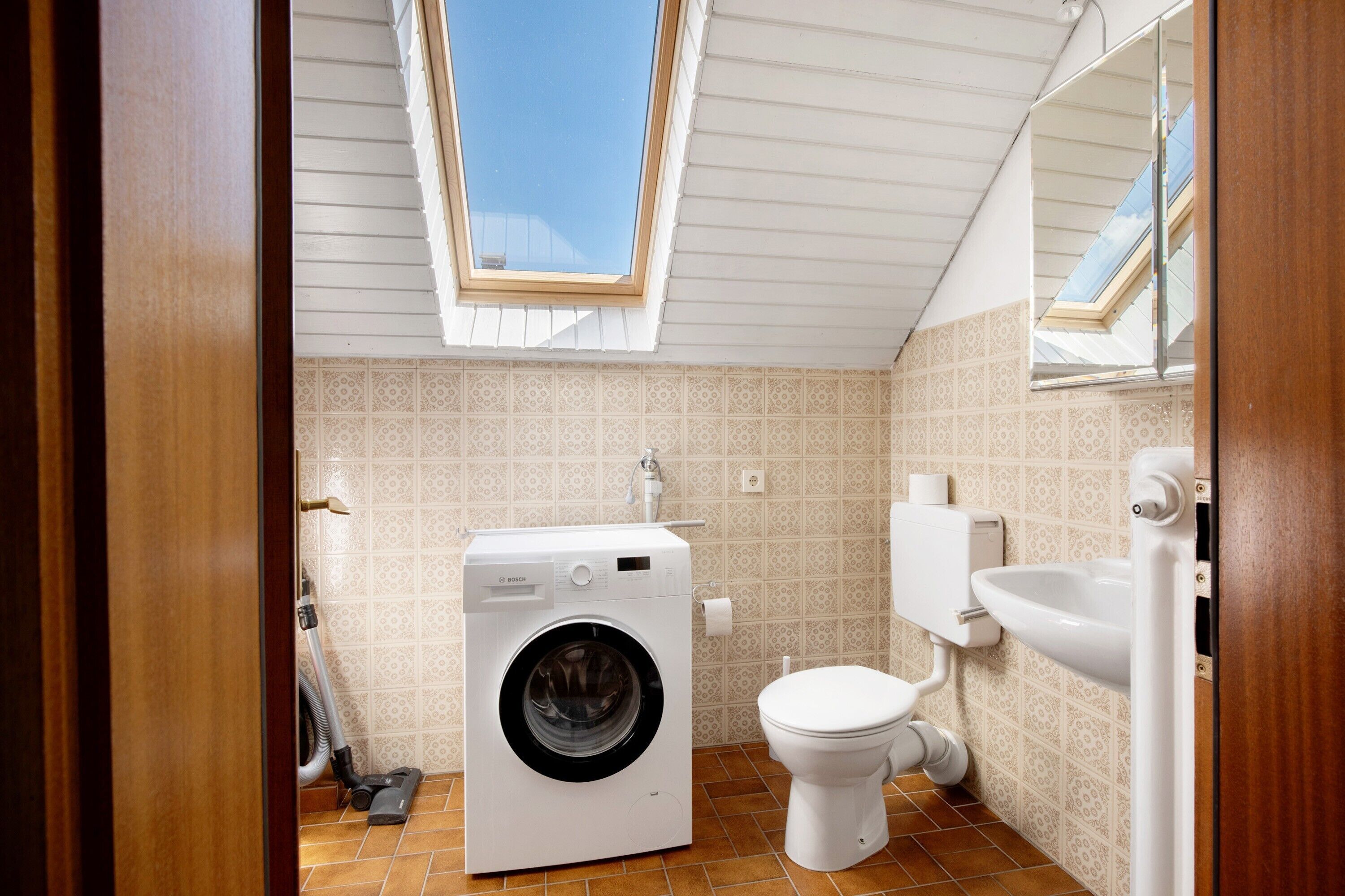 Ein kleines Badezimmer mit Waschmaschine, Toilette und Waschbecken.