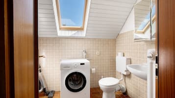 Ein kleines Badezimmer mit Waschmaschine, Toilette und Waschbecken.