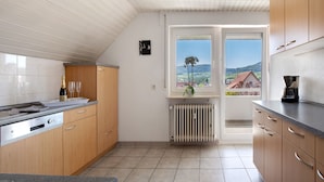 A kitchen with wooden cabinets, a built-in oven, and a window with a view of the countryside. - Apartment 'Ferienwohnung Lange' with Mountain View, Balcony and Wi-Fi (Waldstetten)