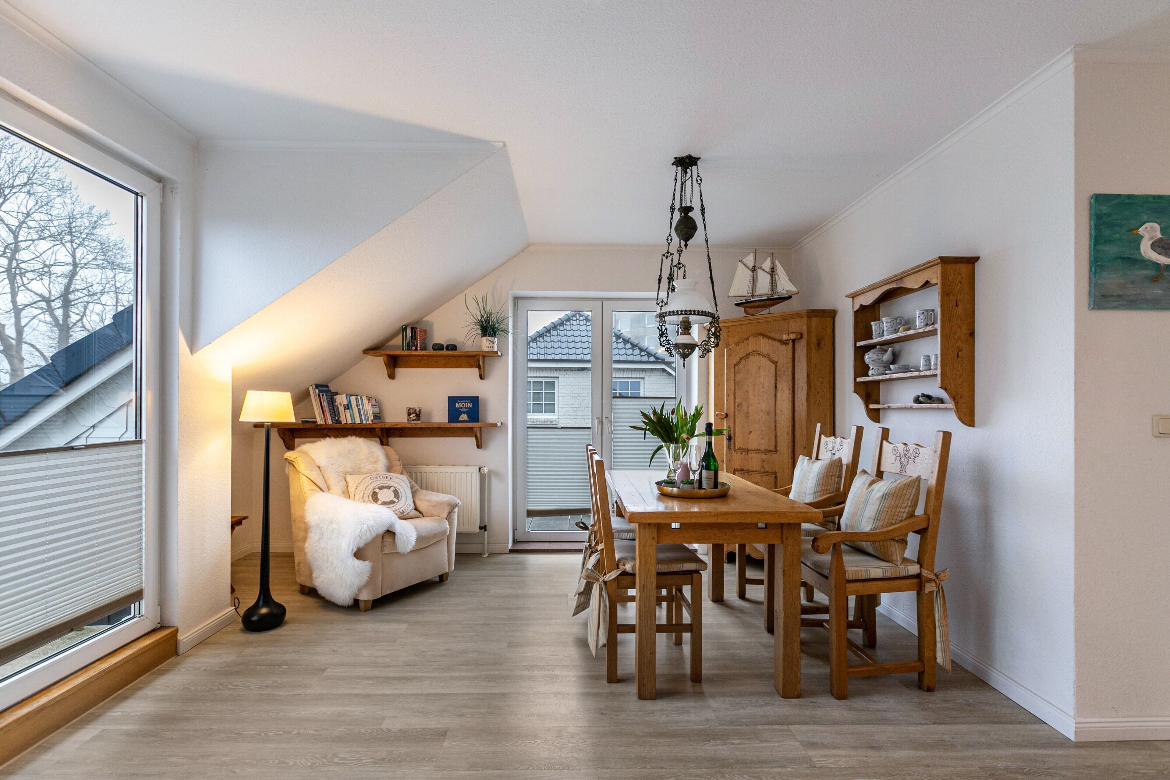 A cozy dining area with a wooden table and chairs, a lamp, and a bookshelf.