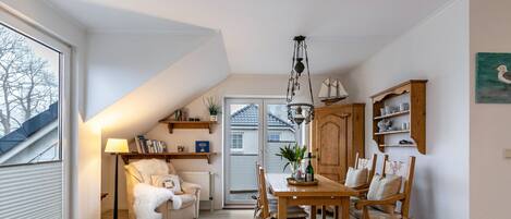 A cozy dining area with a wooden table and chairs, a lamp, and a bookshelf.