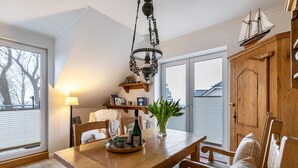 Un comedor con una mesa de madera, sillas, una araña y una decoración náutica en la pared.