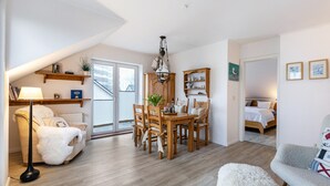 Una habitación acogedora con una mesa de comedor, sillas, una lámpara, un sofá y una cama.