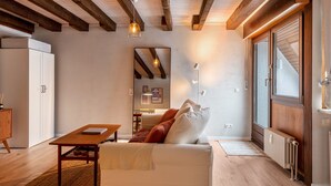 Ein modernes Wohnzimmer mit Holzbalkendecke, einer Couch, einem Tisch und einer Heizung.