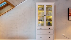 Ein weißer Schrank mit Glastüren, Holzboden und einer schrägen Decke mit Dachfenster.