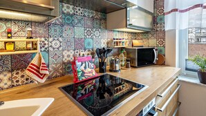 Une cuisine moderne dotée d’une plaque de cuisson à induction noire, de meubles en bois, d’un four à micro-ondes et d’un dosseret carrelé.