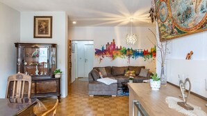 Un salon comprenant une table à manger en bois, un canapé, une grande carte murale et un luminaire suspendu au plafond.